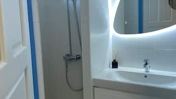 Une salle de bain avec une douche, un lavabo et un miroir.