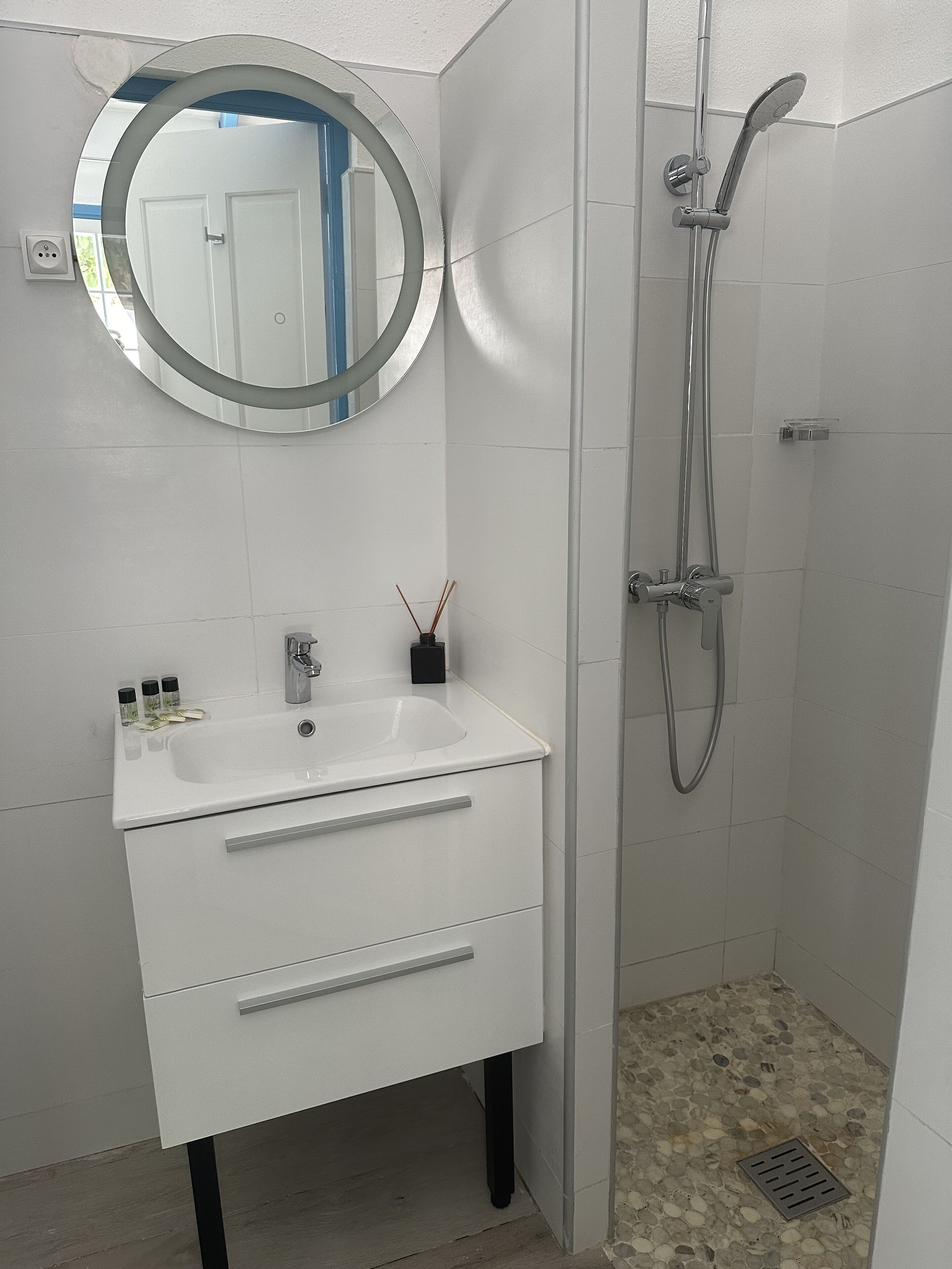 A bathroom with a white sink, mirror, and shower.