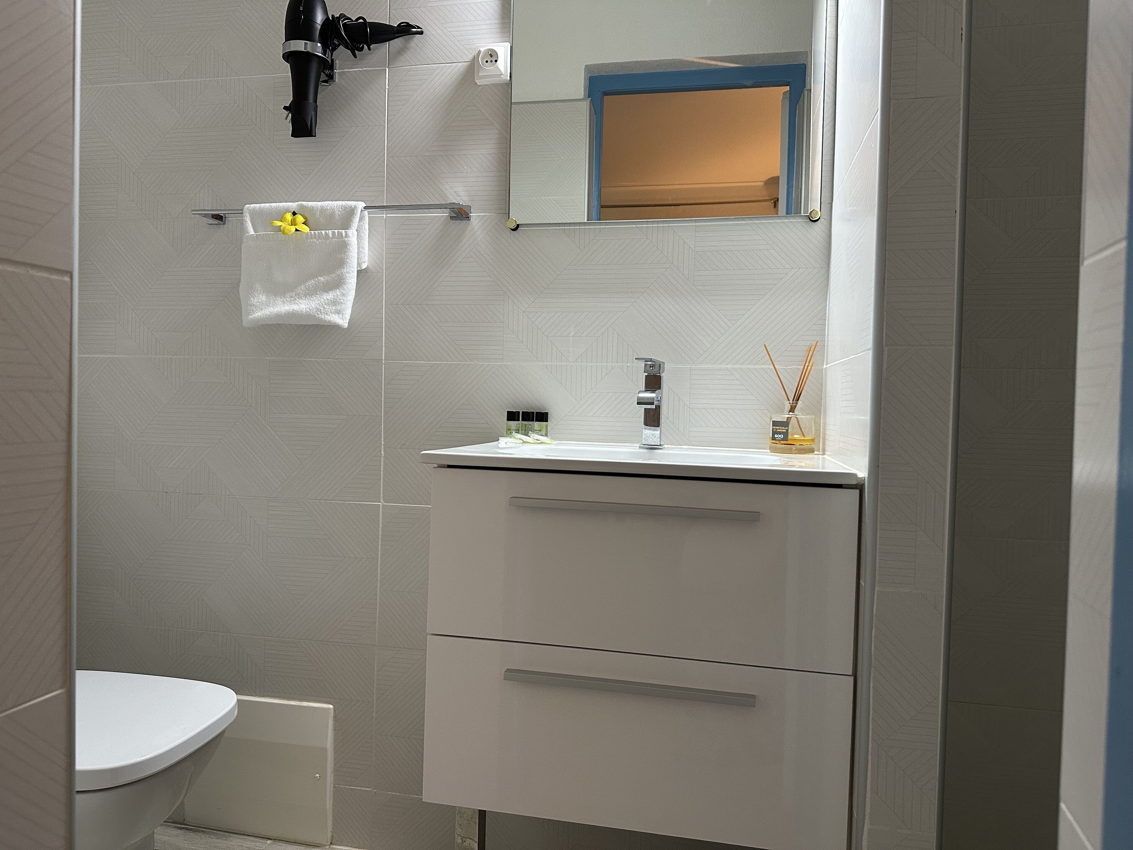 A modern bathroom with a white toilet, a sink with a mirror above it, and a towel rack with a white towel.