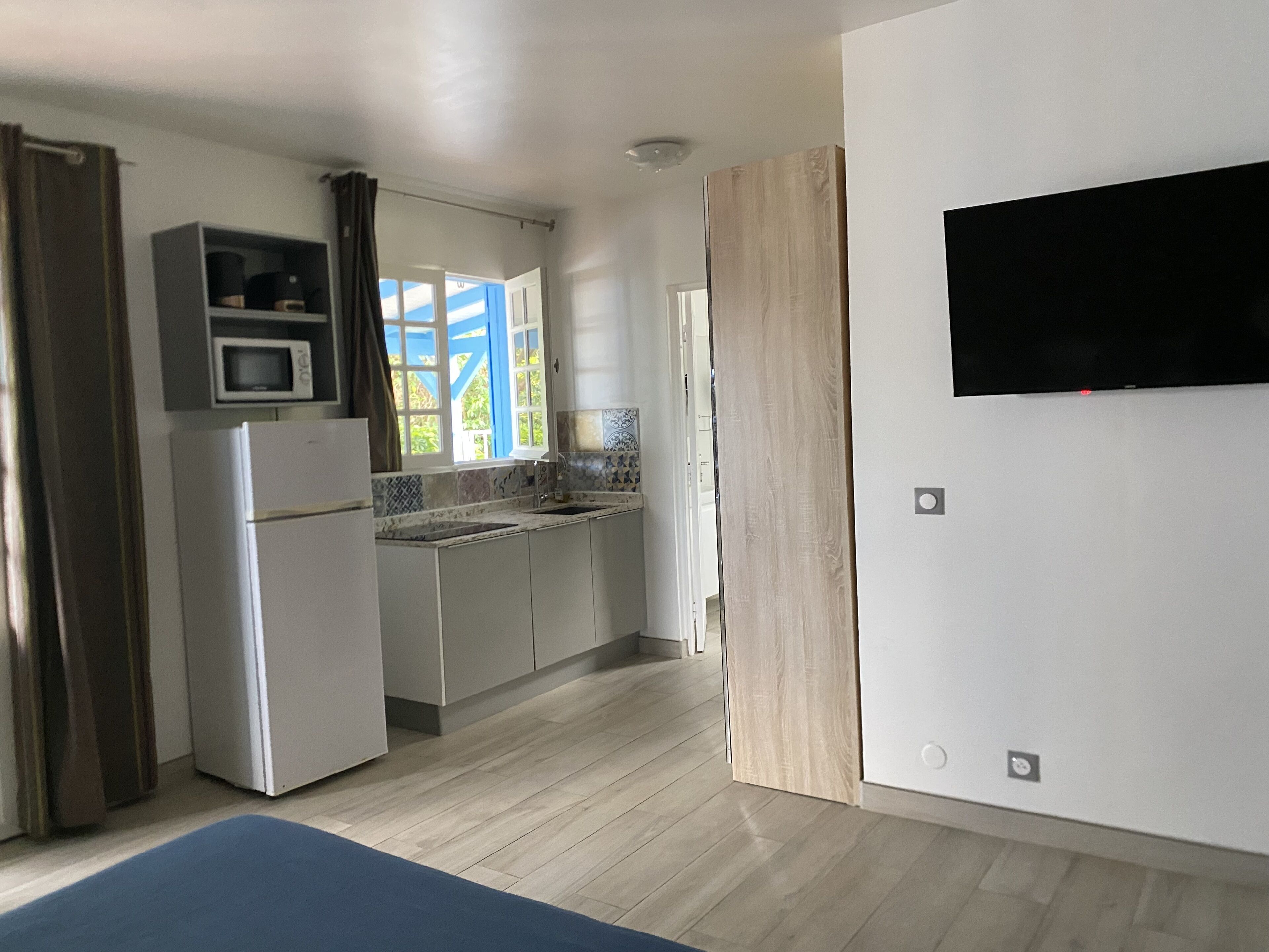 A compact kitchen with a microwave, refrigerator, and a large window.