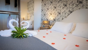 Ein Hotelzimmer mit einem ordentlich bezogenen Bett, einem Nachttisch mit Lampe und blumigem Wandpapier.