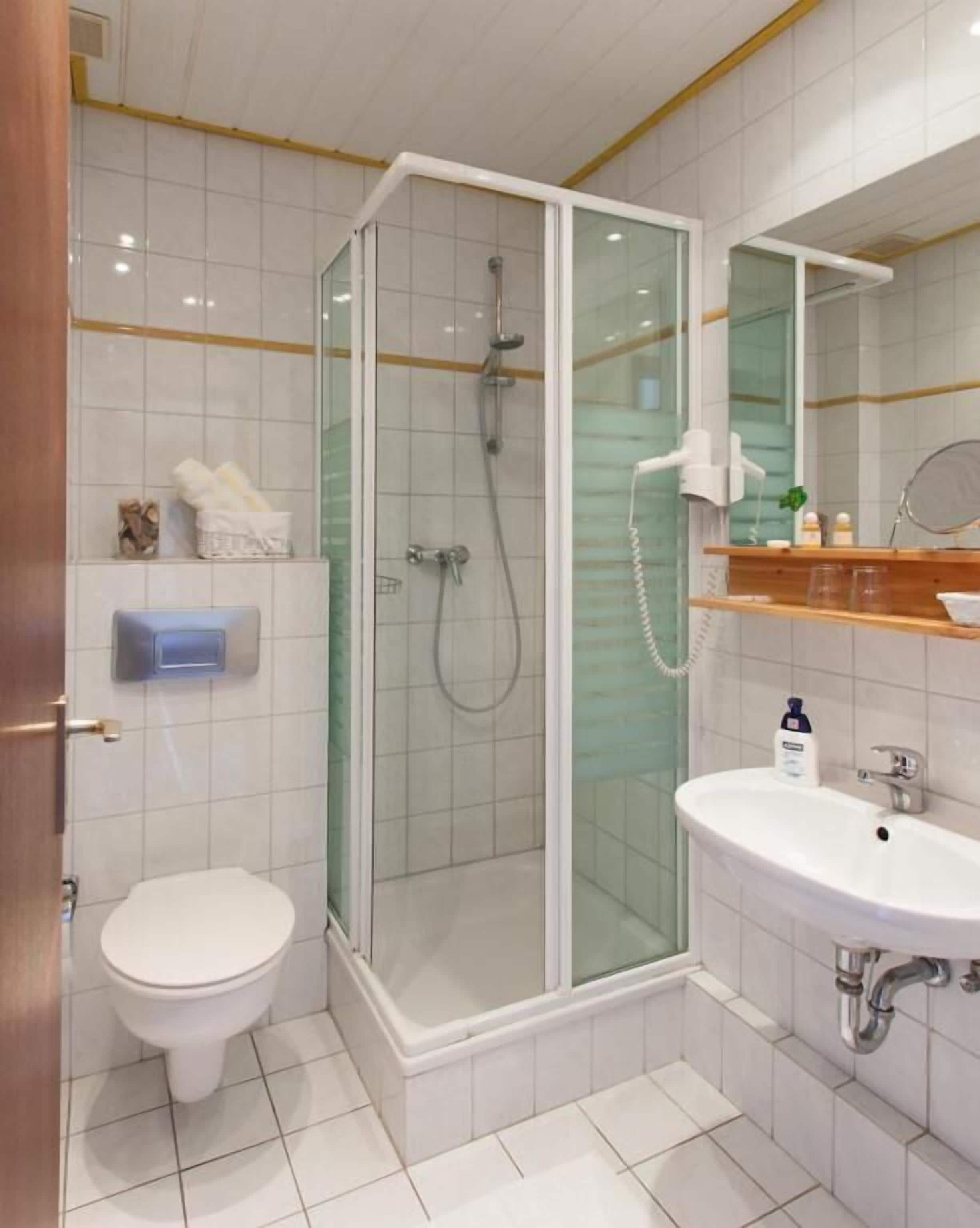 Une salle de bain moderne avec une douche à parois de verre, des toilettes, un lavabo et un miroir.