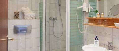 A modern bathroom with a glass-enclosed shower, a toilet, a sink, and a mirror.