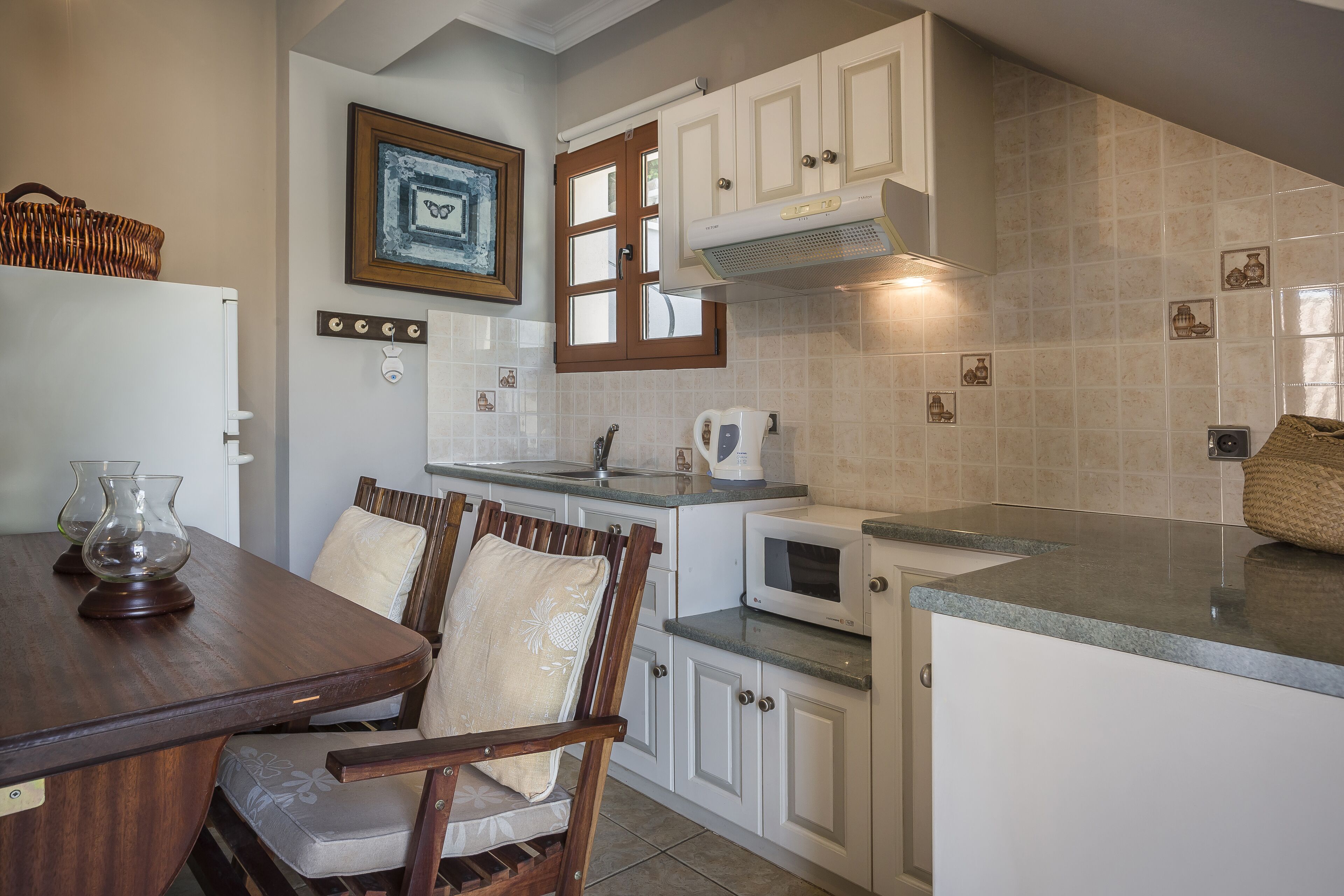 A kitchen with white cabinets, a microwave, and a dining table with chairs.