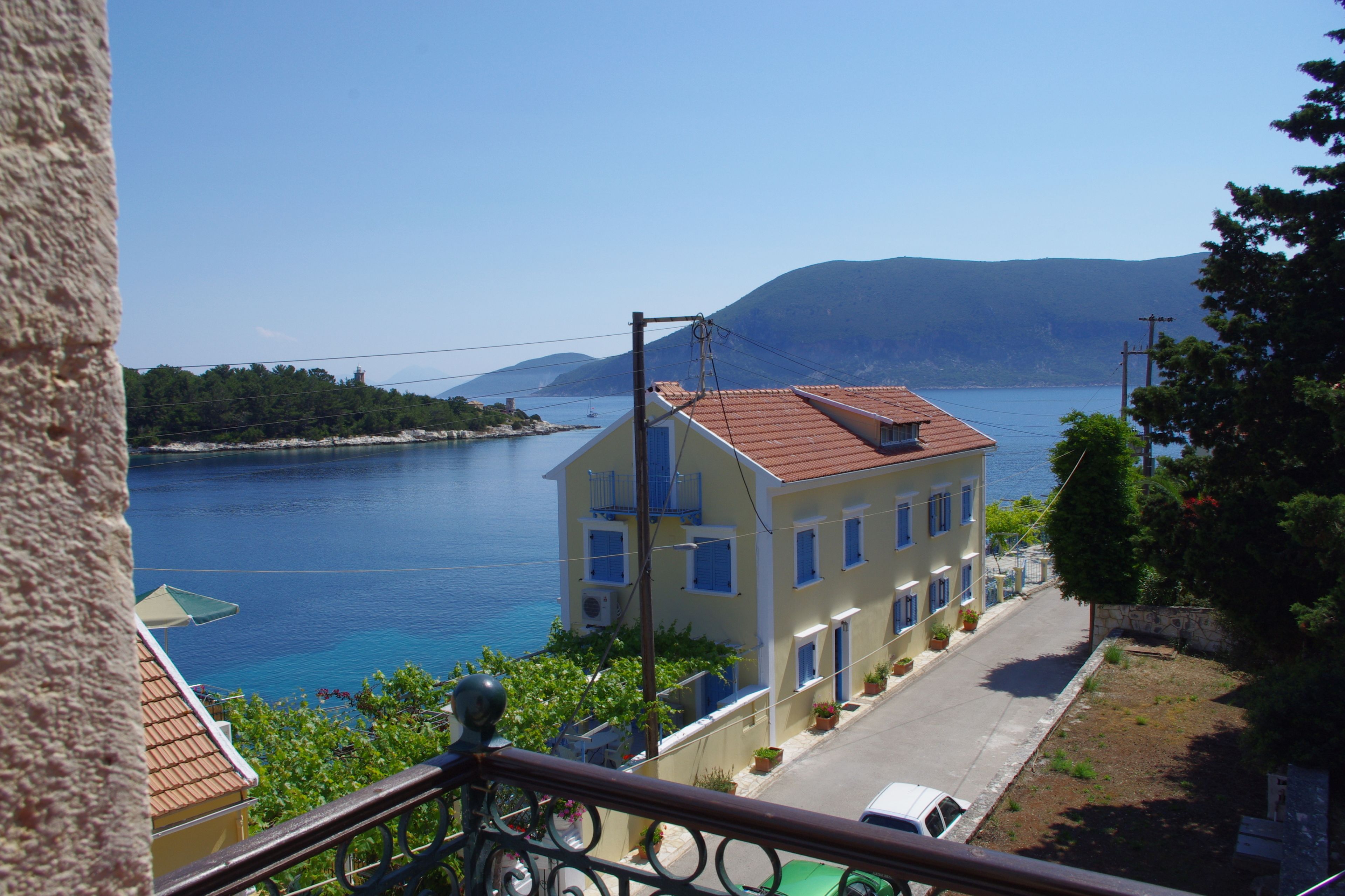 A coastal building with a red roof, a balcony, and a view of the sea.