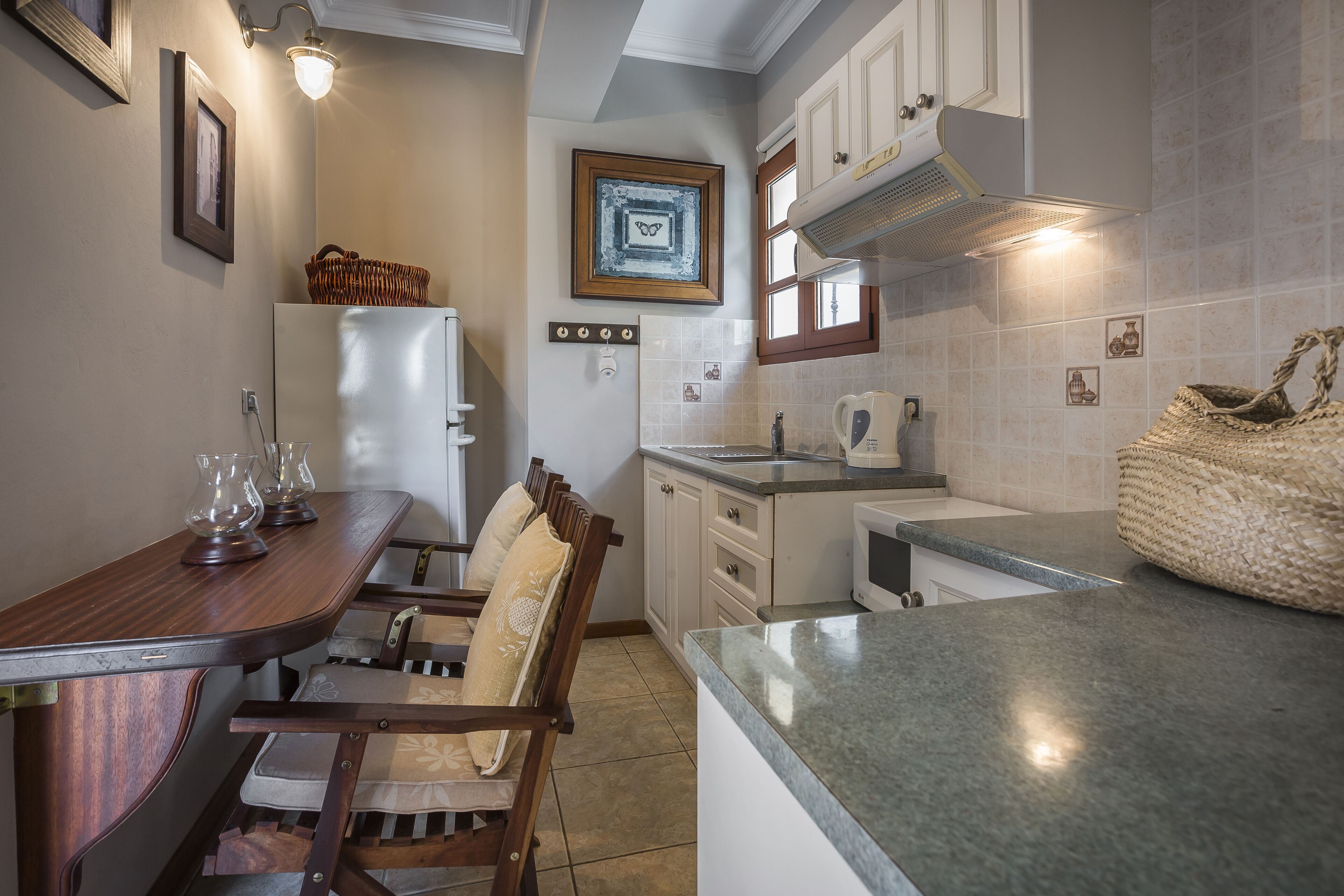 A compact kitchen with a dining area, featuring a refrigerator, microwave, and a small sink.