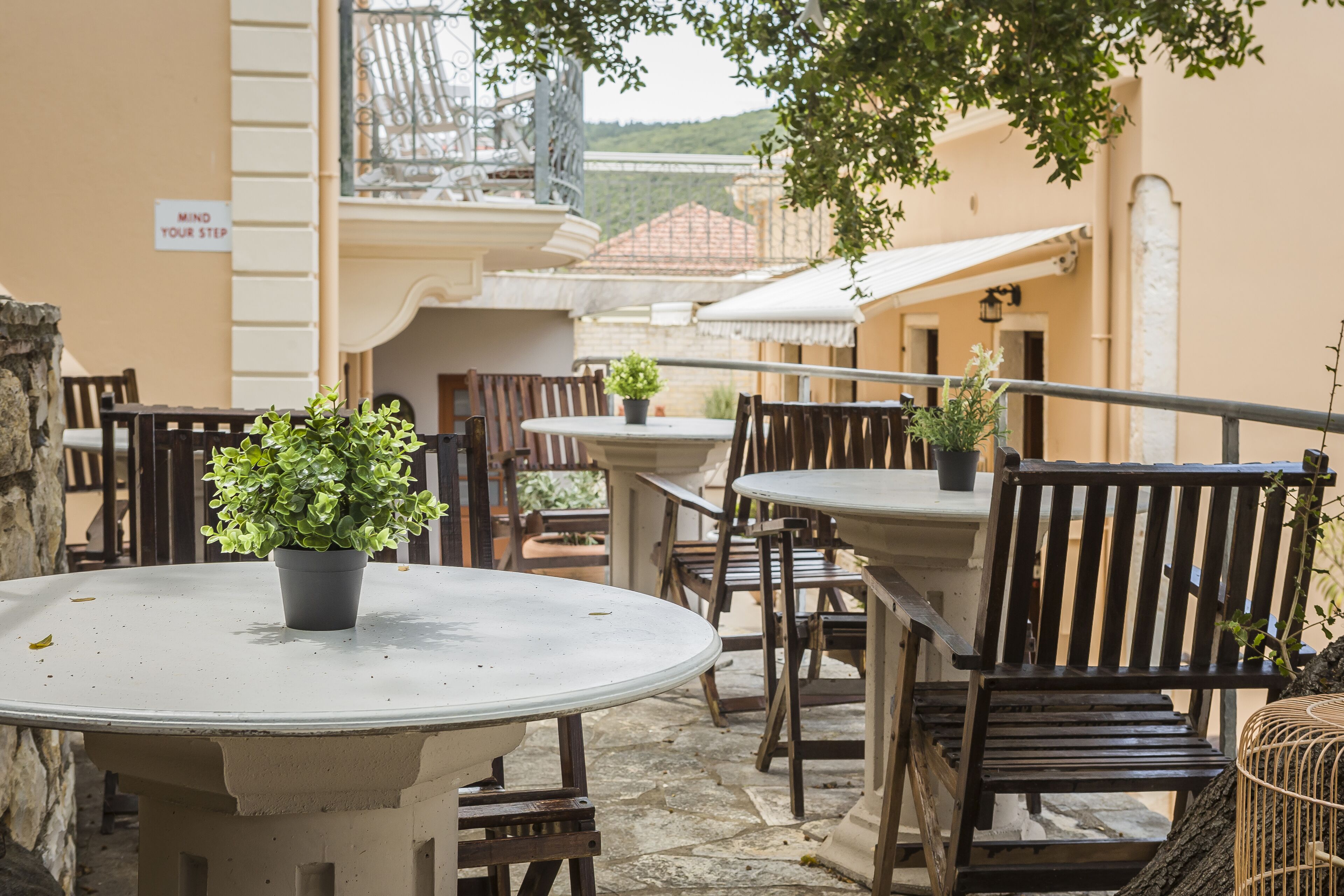 Un espace extérieur aménagé avec des tables rondes et des chaises en bois, entouré de murs en pierre et agrémenté de plantes en pot.