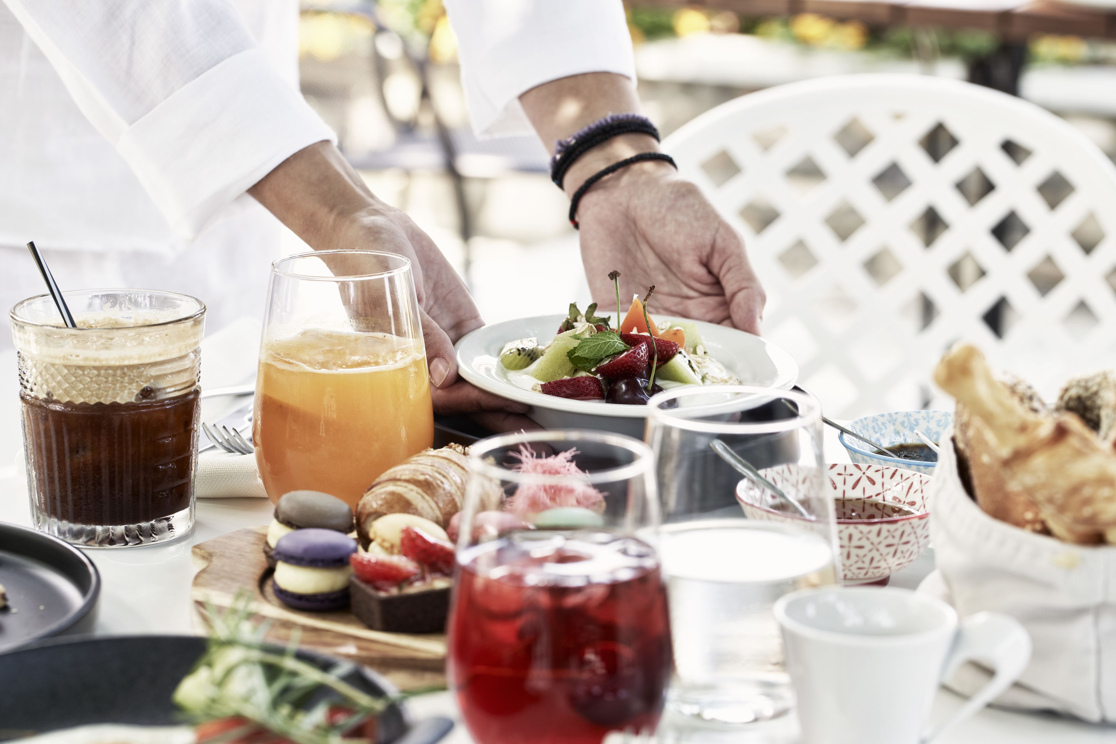 A table set with a variety of food items, including a plate of salad, a glass of orange juice, and a glass of red beverage.