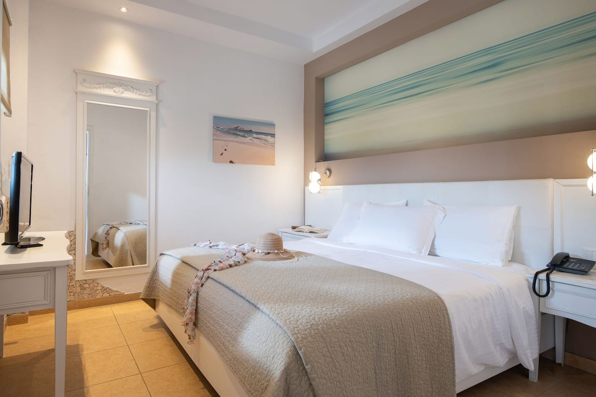 Una habitación de hotel con cama, mesita de noche, lámpara y un cuadro en la pared.