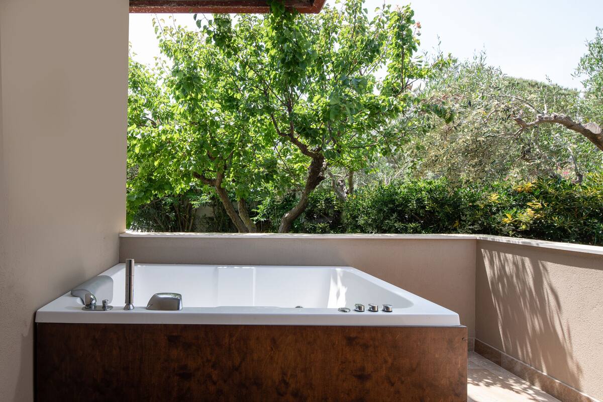 Un baño moderno con una bañera independiente, y un ventanal con vistas a un jardín con árboles y arbustos.