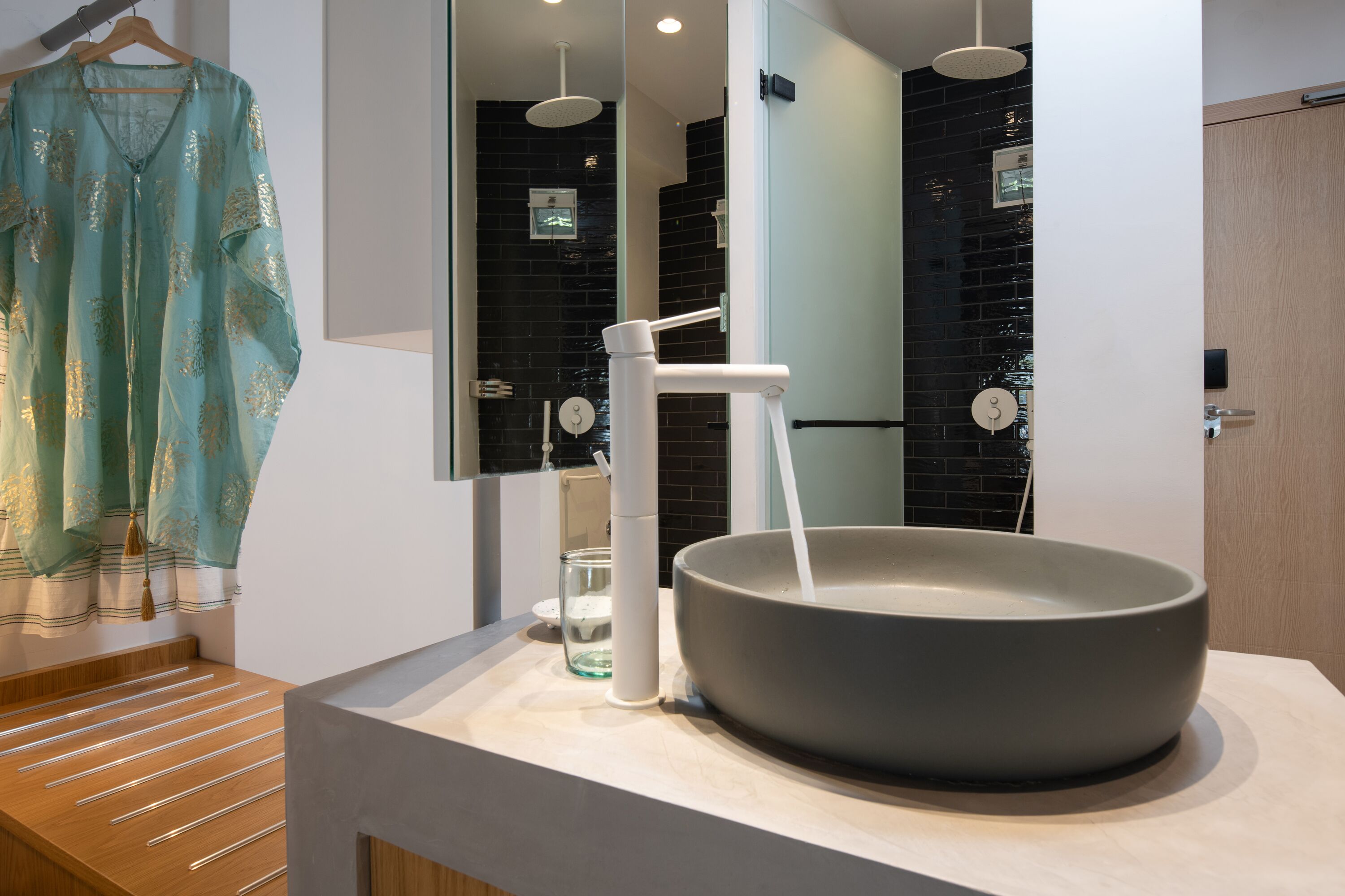 A modern bathroom with a large basin sink, a towel rack, and a mirror.