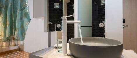 A modern bathroom with a large basin sink, a towel rack, and a mirror.