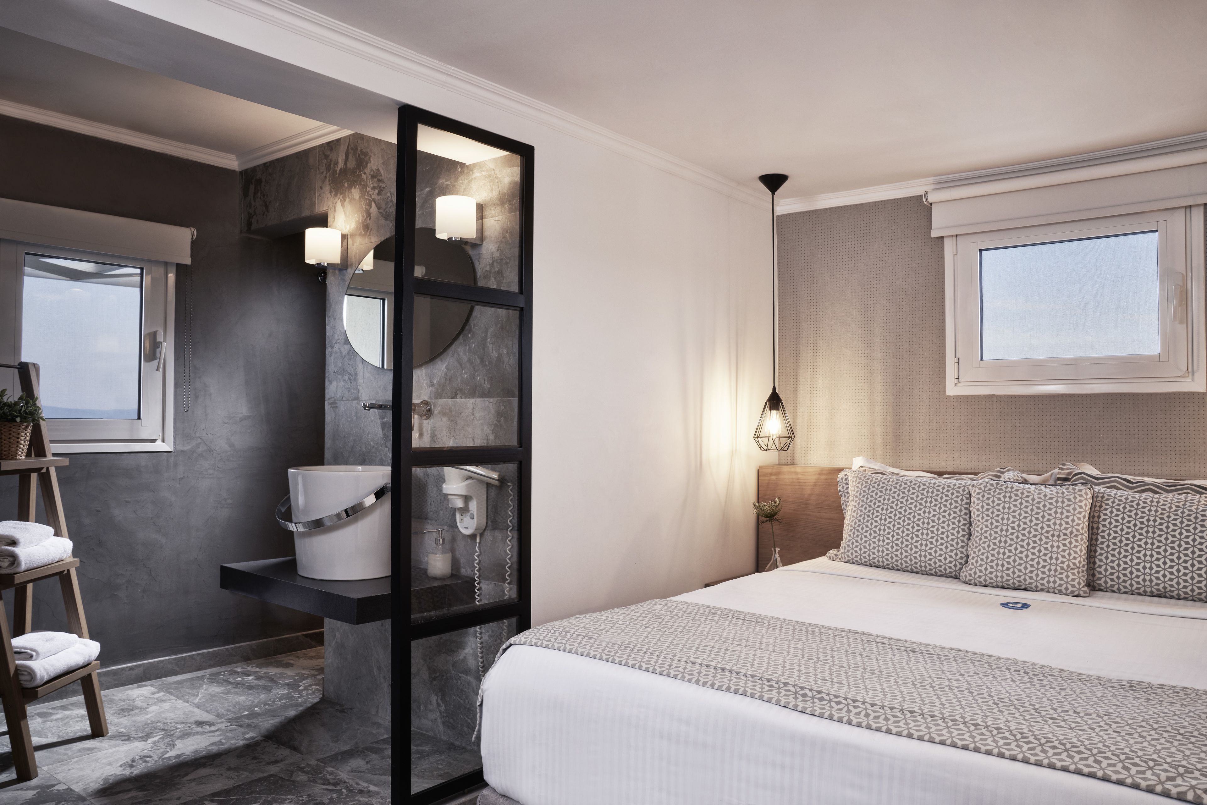 Un baño moderno con un espejo grande, un lavabo blanco y un perchero para toallas.