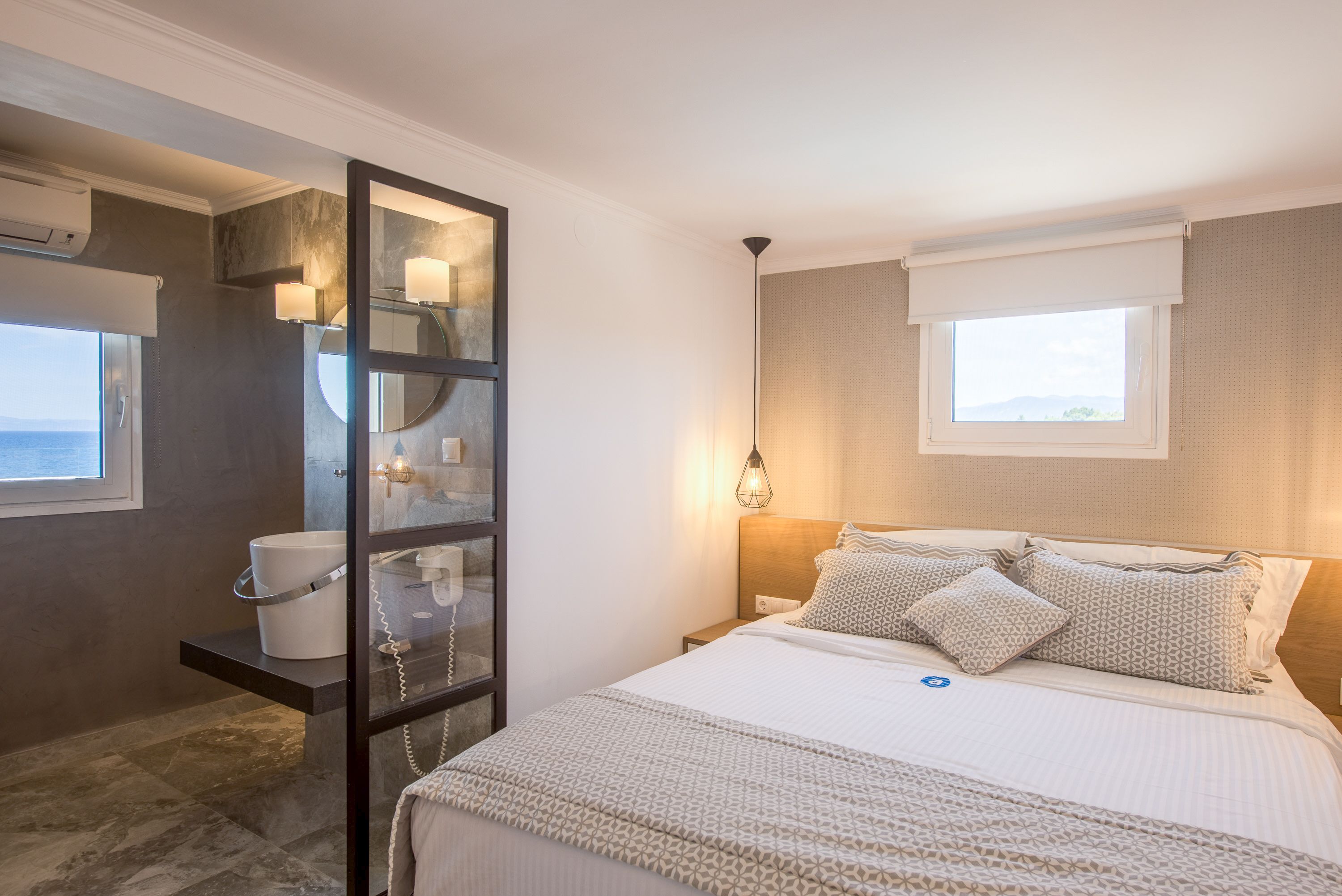 Une chambre à coucher avec un lit, une table de chevet et une grande fenêtre.
