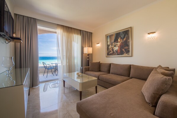 Una habitación de hotel moderna con una mesita de vidrio, un sofá color beige y un cuadro en la pared.
