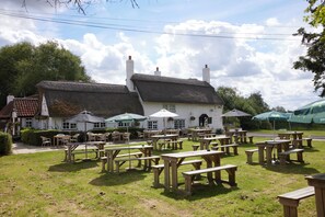 A traditional building with a thatched roof, surrounded by outdoor seating areas with tables and chairs.