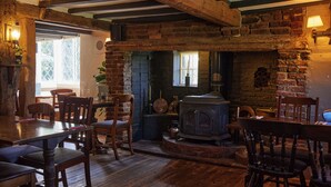 A rustic interior with exposed wooden beams, a brick fireplace, and wooden furniture. - Old Ferry Boat St Ives by Greene King Inns (St Ives)