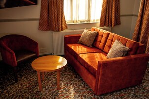 A living room with a red sofa, a wooden coffee table, and patterned carpet.