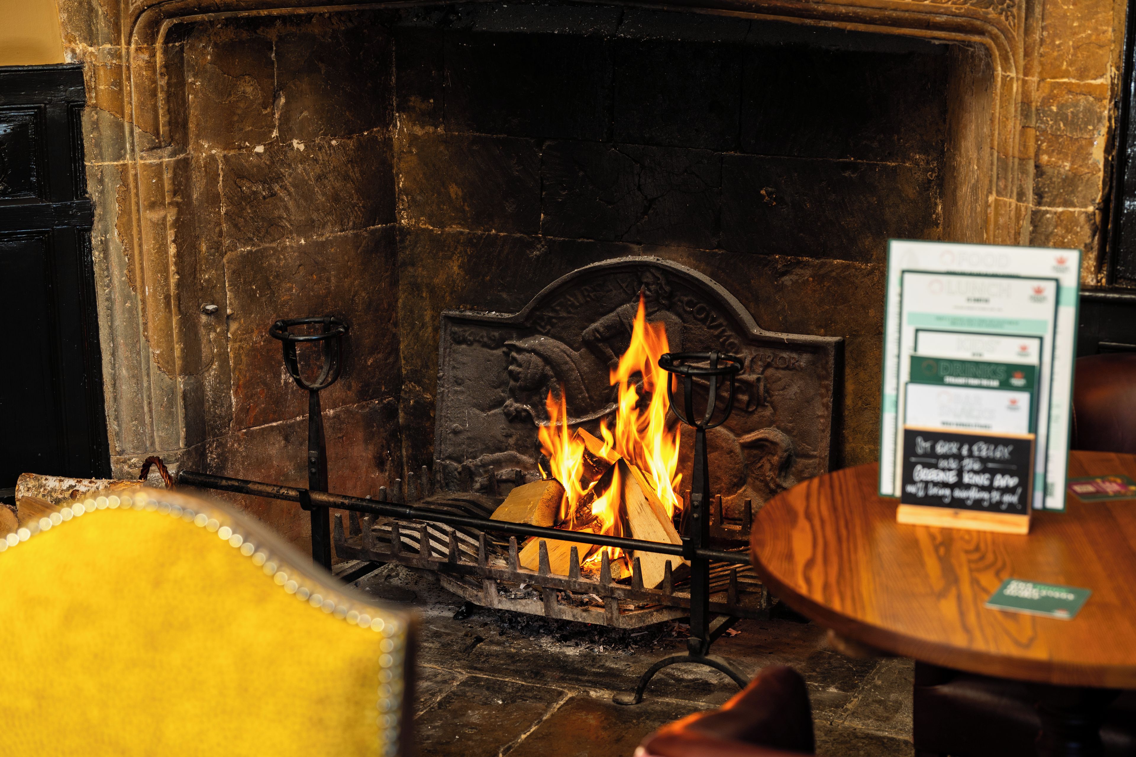 A fireplace with a fire, a sign with text, and a wooden table with a menu.