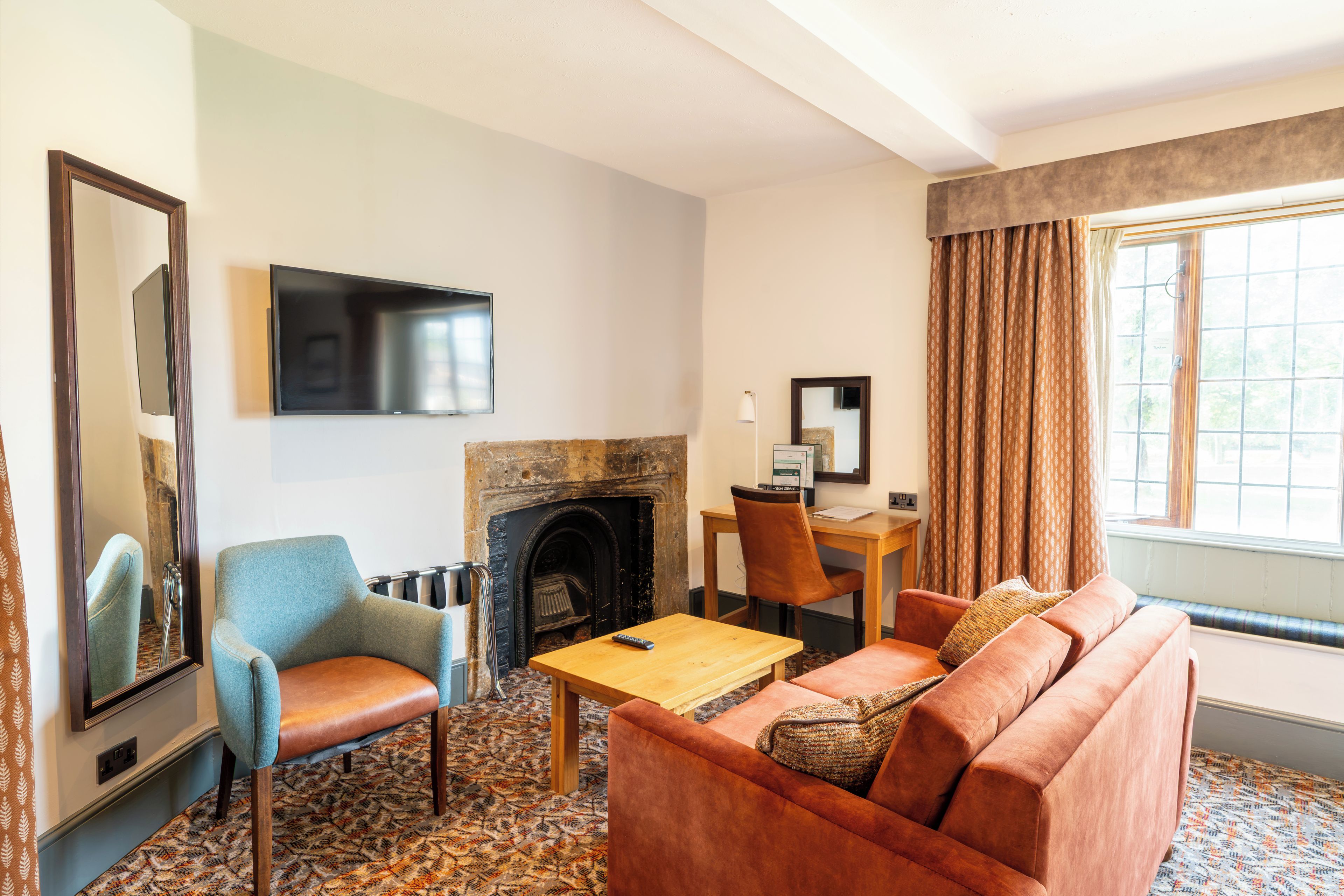 A living room with a fireplace, a television mounted on the wall, a sofa, a chair, and a table.