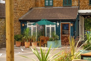 A building with a tiled roof, a door labeled 'HOTEL GUESTS ONLY,' and a seating area with tables and chairs. - Red Lion Hotel Adderbury by Greene King Inns (Banbury)