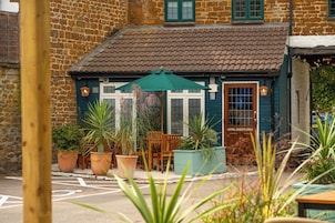 A building with a tiled roof, a door labeled 'HOTEL GUESTS ONLY,' and a seating area with tables and chairs.