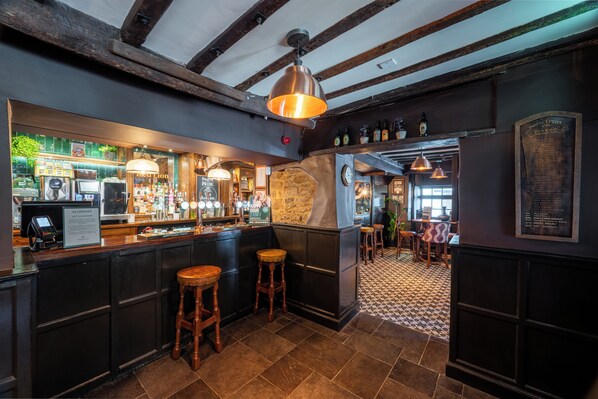 A bar area with a counter, stools, and a menu board.