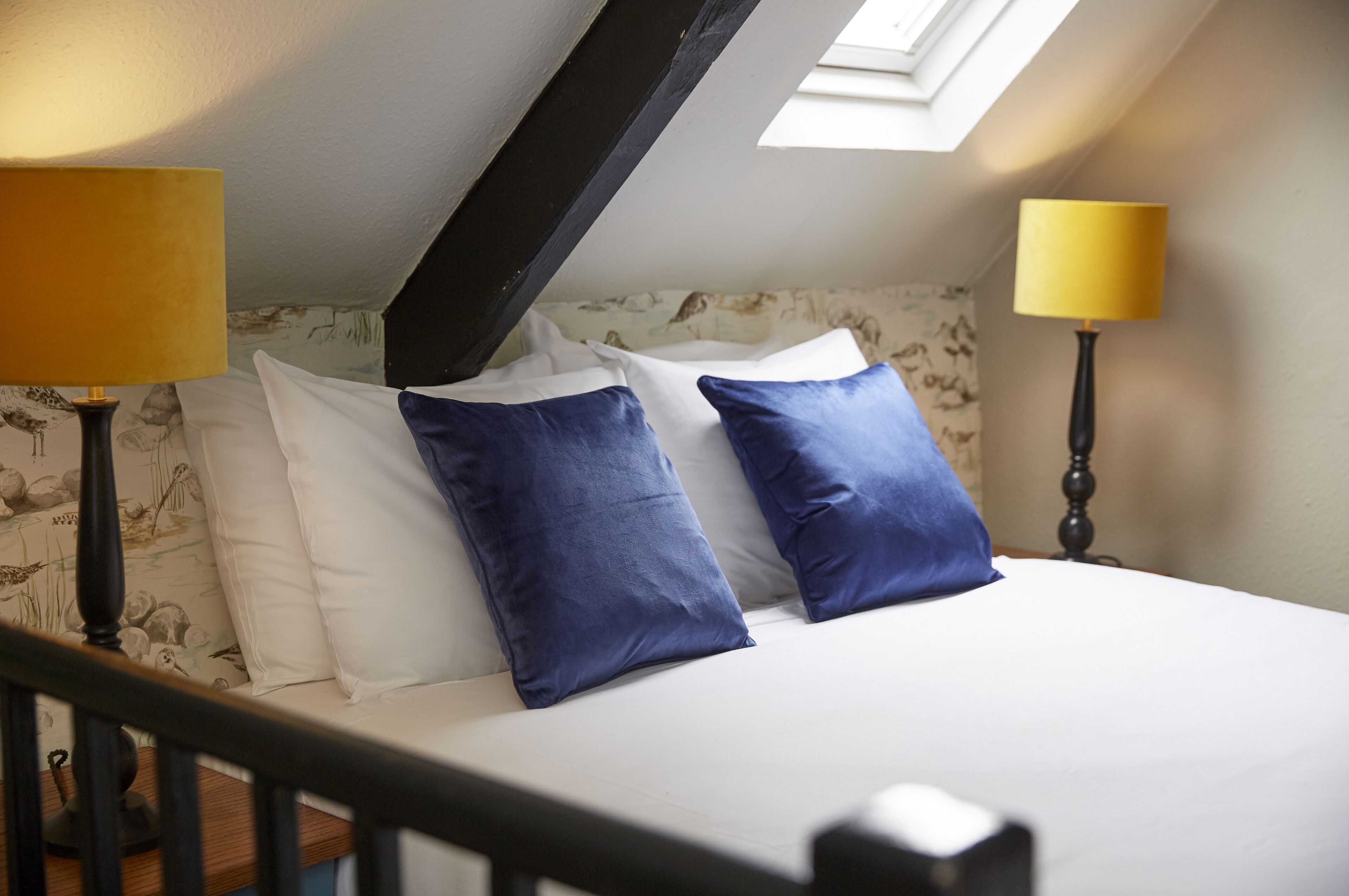 Ein Schlafzimmer mit einem Bett, zwei Lampen und einem Dachfenster.