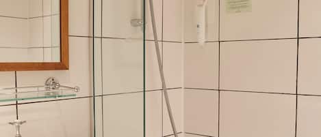 Un baño con ducha de vidrio, lavamanos blanco y bañera.