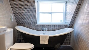 A bathroom with a freestanding bathtub, a toilet, and a window. - Antelope Hotel by Greene King Inns (Poole)