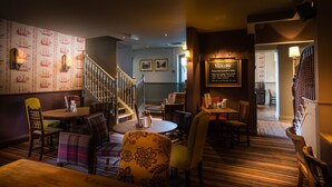 A restaurant with a staircase, wooden chairs, and tables. There is a sign on the wall and a lamp on the floor. - Antelope Hotel by Greene King Inns (Poole)