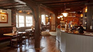 A rustic bar area with wooden beams, a bar counter, and seating. - White Hart Hotel by Greene King Inns (Colchester)