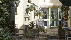 A quaint cafe with a green door, outdoor seating, and hanging plants. - White Hart Hotel by Greene King Inns (Colchester)