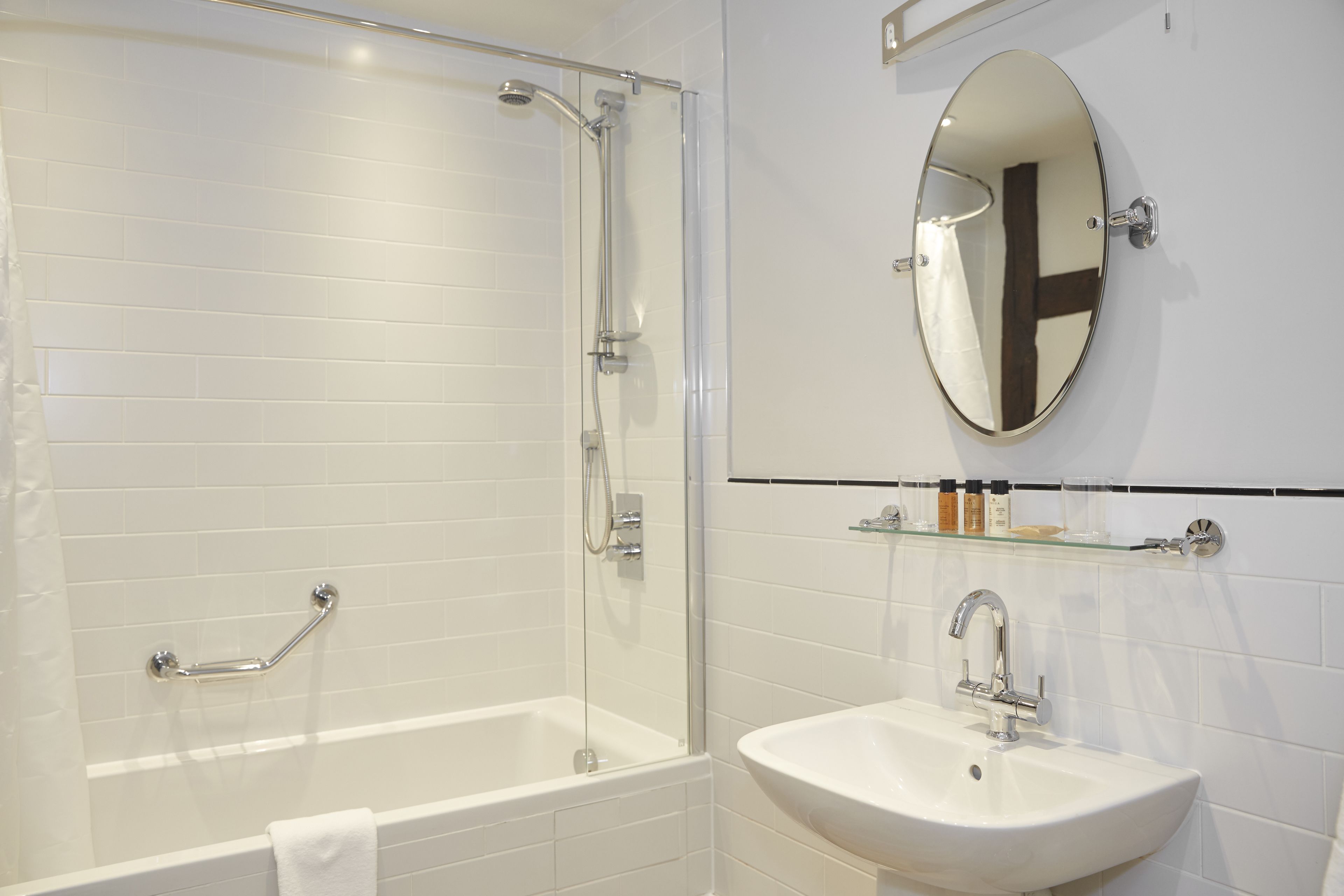 Un baño moderno con ducha de vidrio, una bañera blanca y un lavabo con espejo.