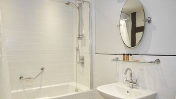 Un baño moderno con ducha de vidrio, una bañera blanca y un lavabo con espejo.