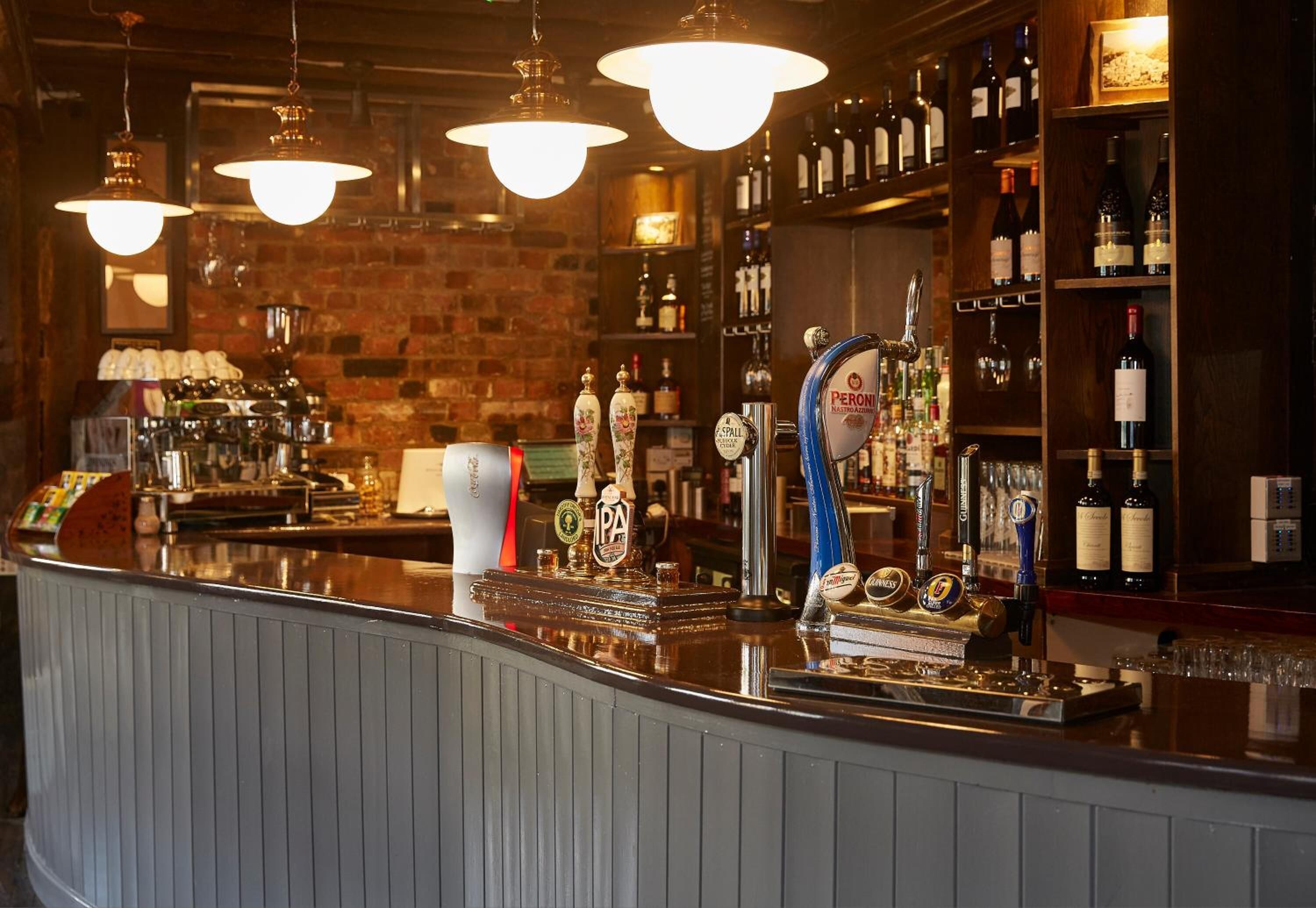 Een bar met een toonbank, meerdere bierkraan en flessenrekken.