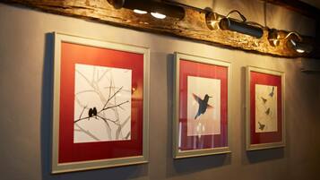 Three framed artworks on a wall with a rustic wooden beam above.
