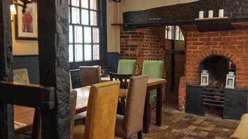 Un interior de pub tradicional con paredes de ladrillo, chimenea y mobiliario de madera.