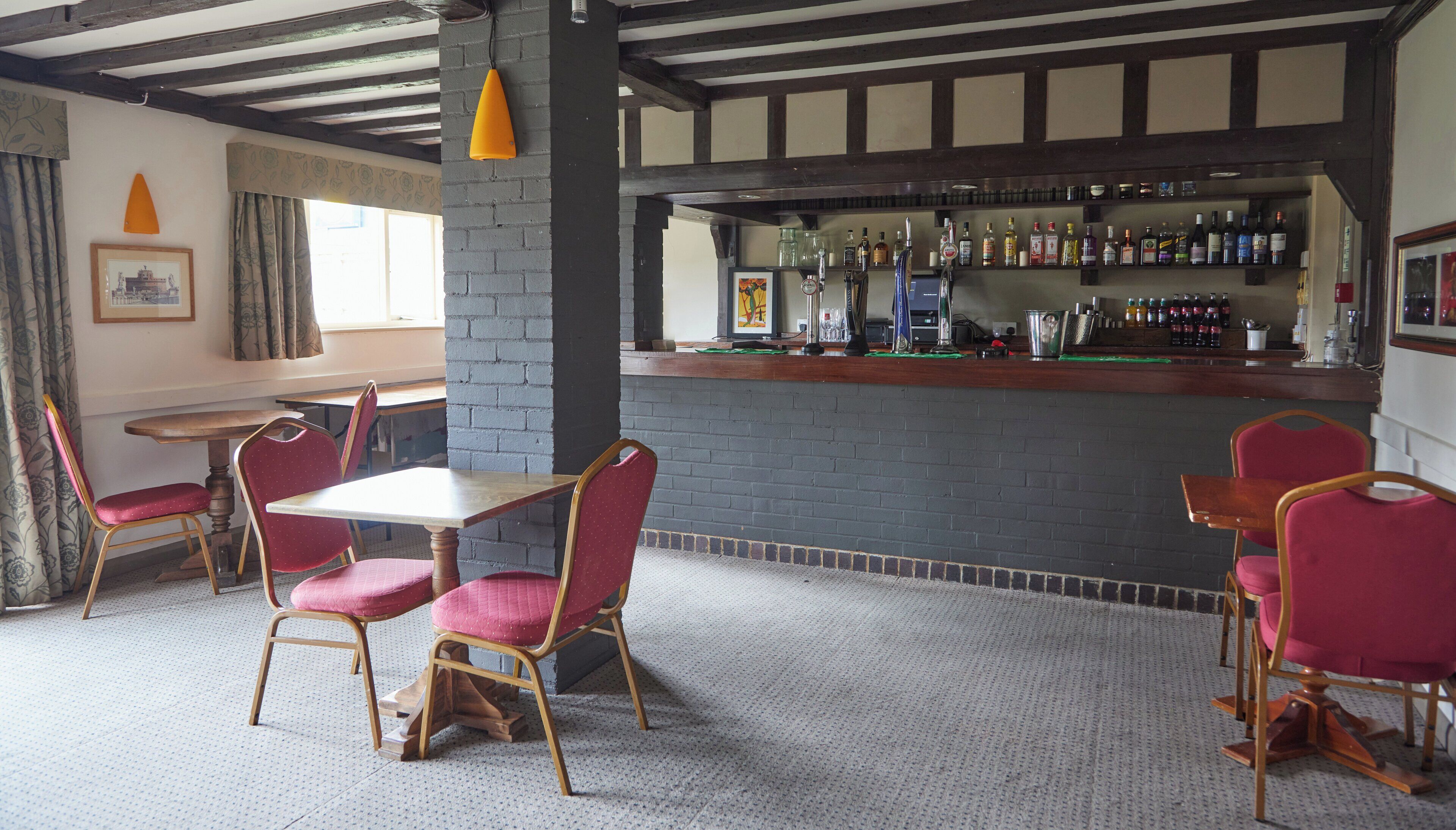 A bar area with a brick wall, wooden ceiling beams, and a variety of liquor bottles.