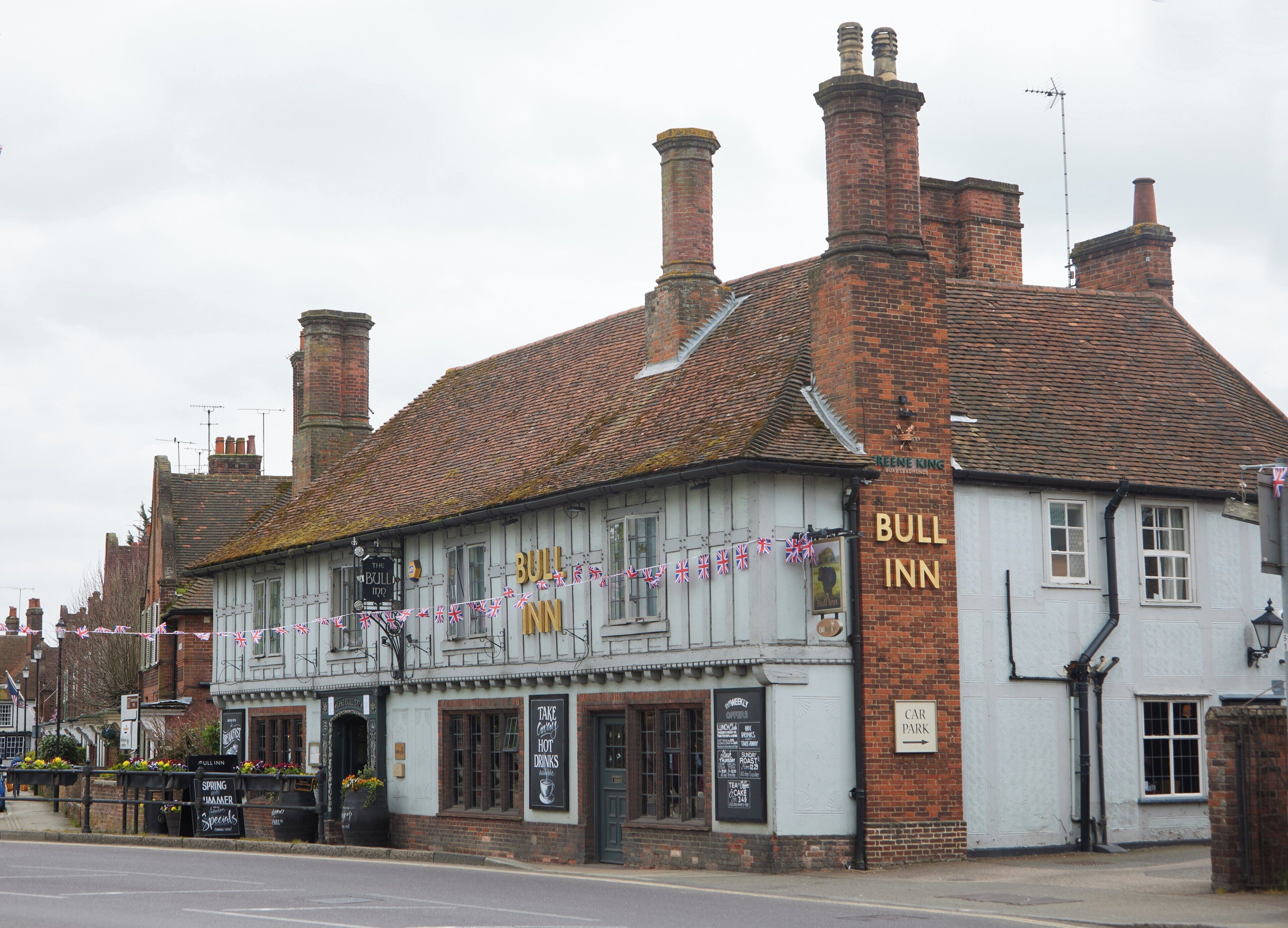 A traditional pub named 'Bull Inn' with a signboard, a car park sign, and a British flag decoration.