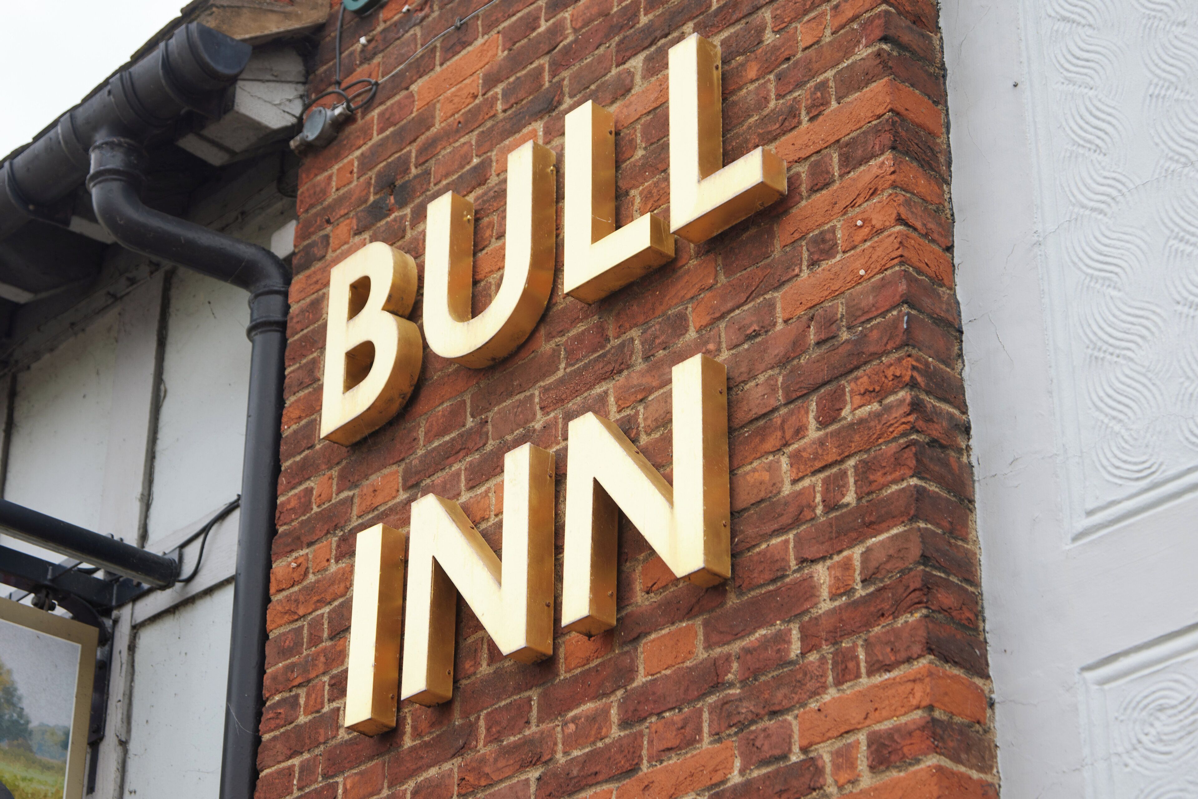A brick wall with the words "BULL INN" in large, wooden letters.