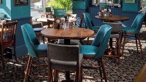 A cozy restaurant with teal walls, wooden tables, and teal upholstered chairs. - Commodore Hotel Bournemouth by Greene King Inns (Bournemouth)