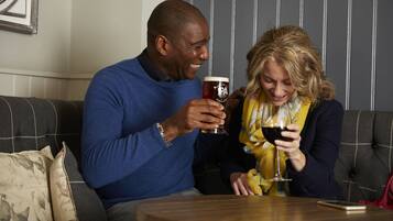 Um homem e uma mulher sentados num sofá, segurando copos de vinho.