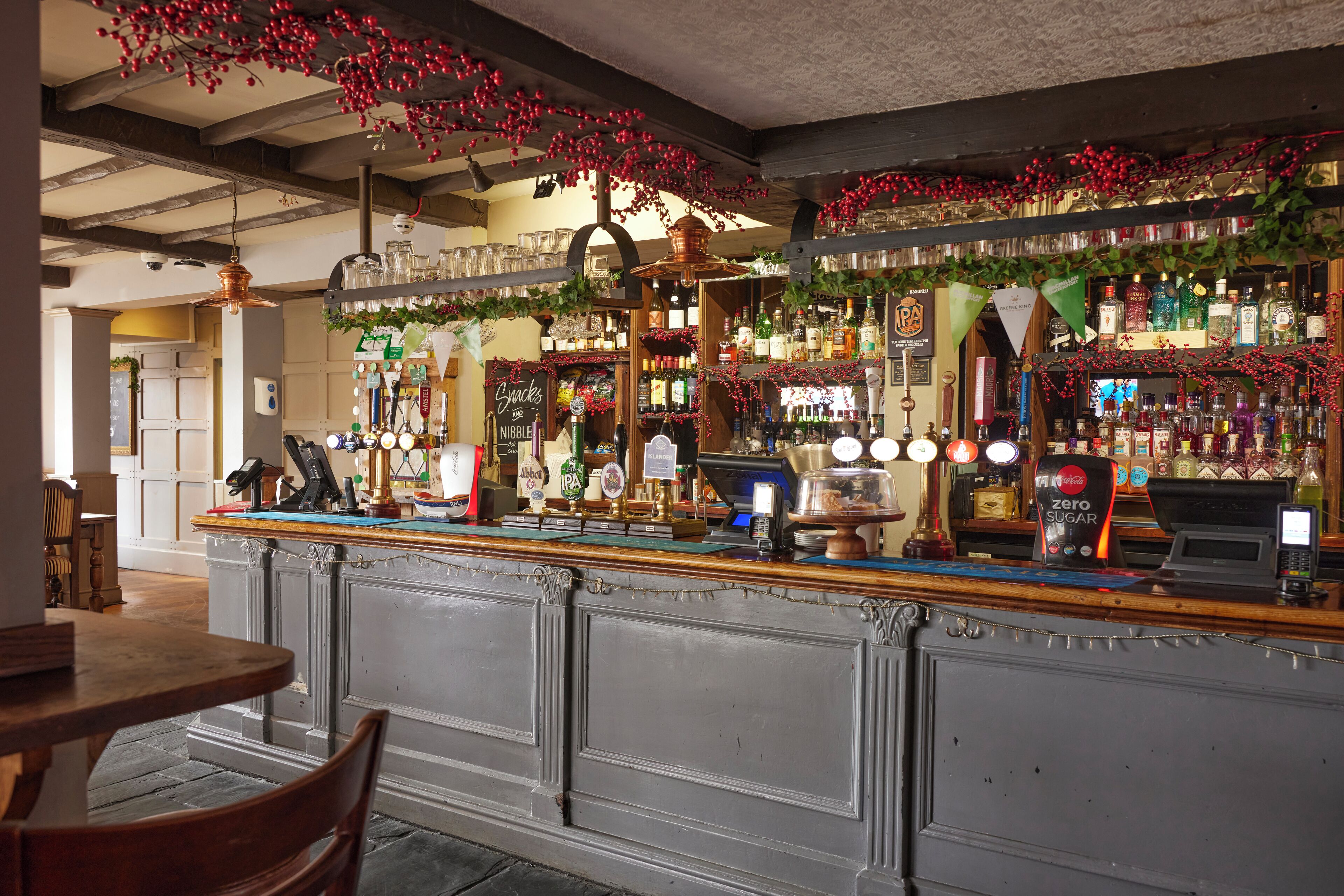 A bar area with shelves of liquor bottles, a cash register, and a decorative hanging garland.