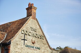 Un edificio con un letrero que dice "The Doghouse" y "Greene King" en su fachada.