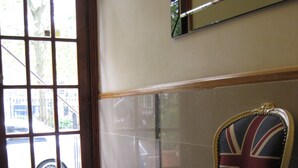 A chair with a Union Jack design in a room with a tiled floor and a door with a window. - Elmwood Hotel (London)
