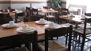 A dining area with tables set for tea service, chairs, and a potted plant. - Elmwood Hotel (London)