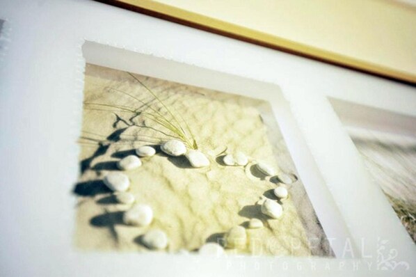 Une œuvre d’art encadrée, avec un fond texturé et une série de pierres blanches disposées en une ligne courbe.