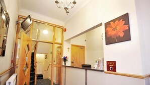 A reception area with a staircase, a flower vase, a mirror, and a 'Keys' sign. - Elmwood Hotel (London)