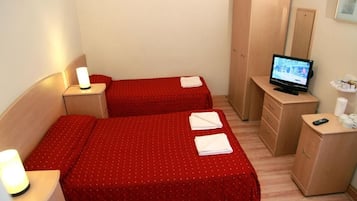 A hotel room with two beds, a TV, a wardrobe, and a bedside table with a lamp.